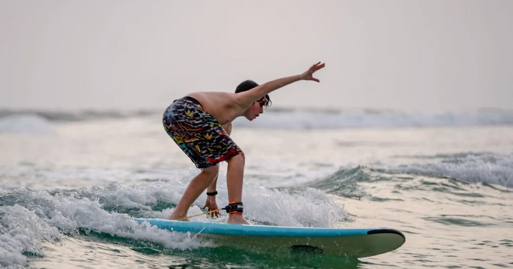 Surfer riding a wave along the tropical coast of Sri Lanka with palm trees in the background.